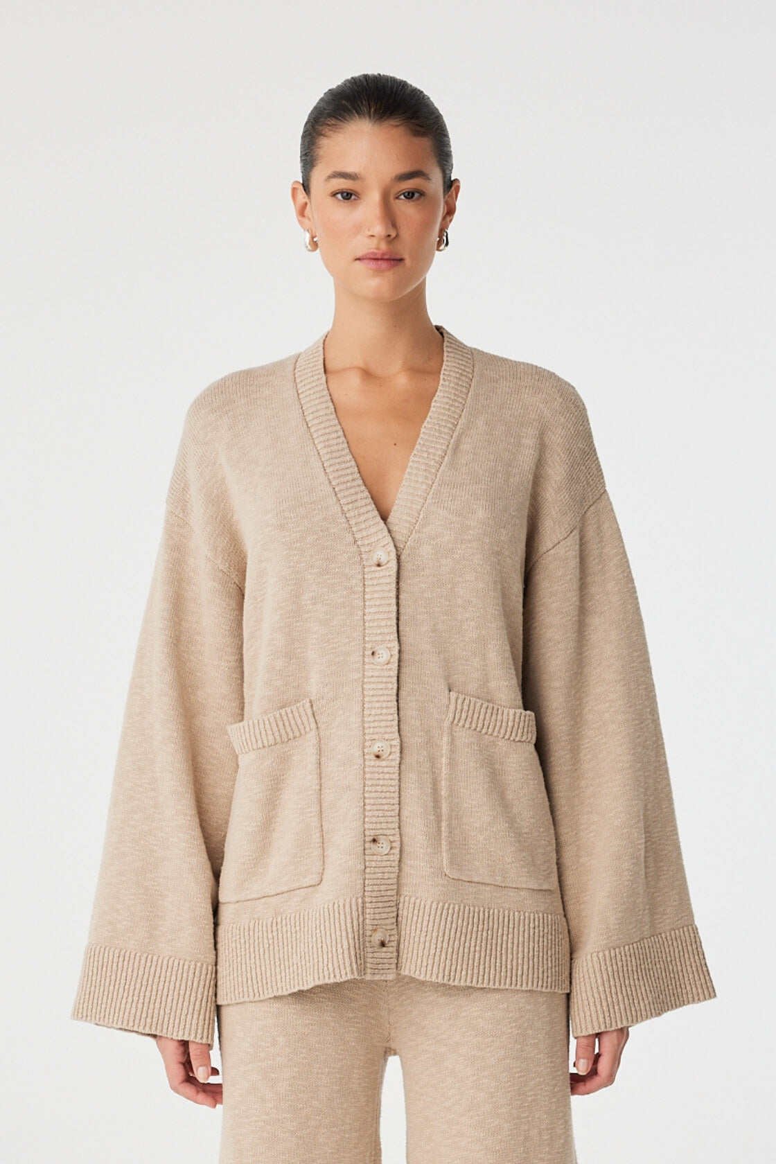 Model wears Emmet Cardigan in taupe organic cotton, relaxed fit with wide sleeves and button-down front.