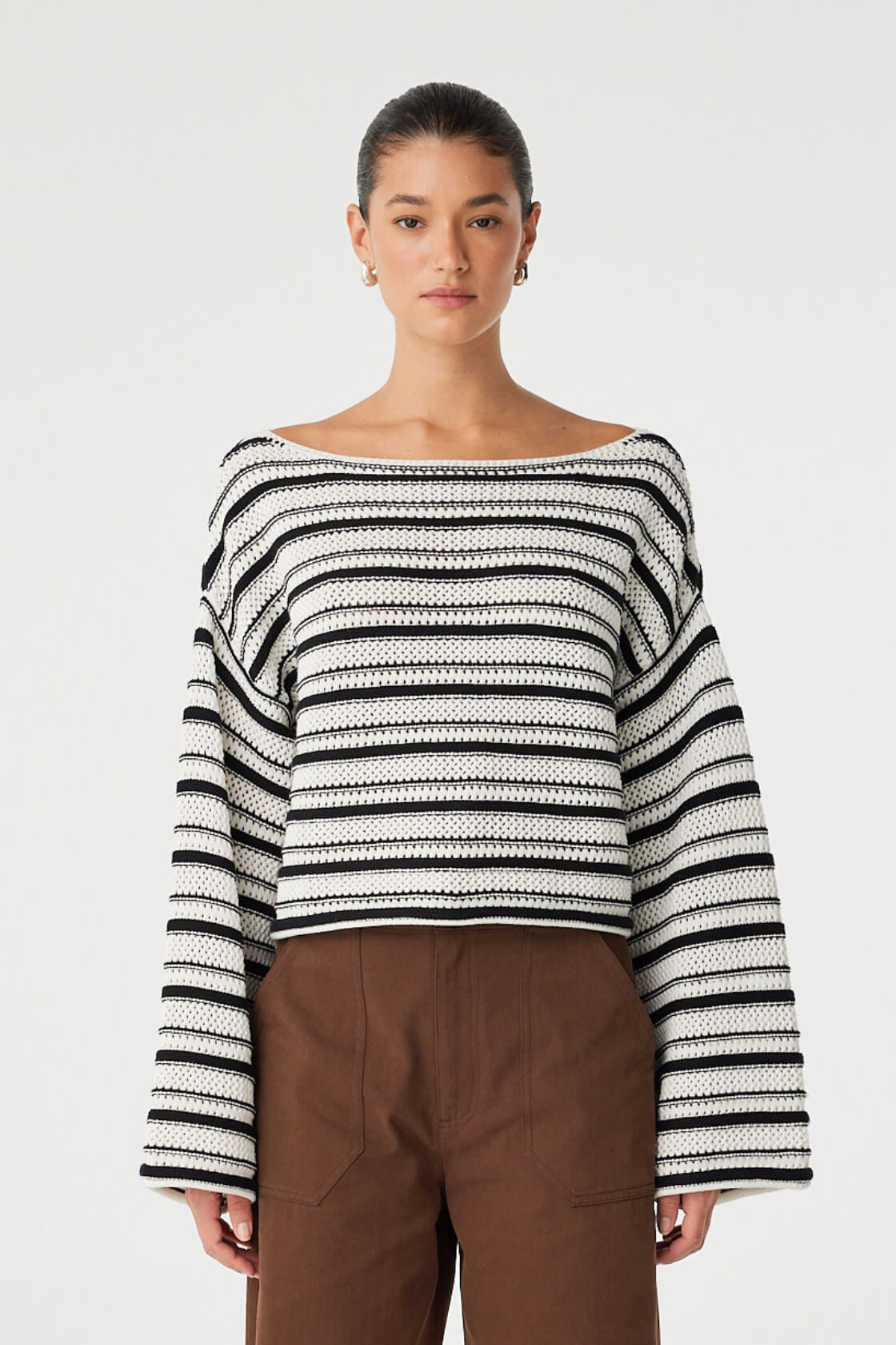 Model wears cream and black striped crochet sweater with wide sleeves and boat neckline.