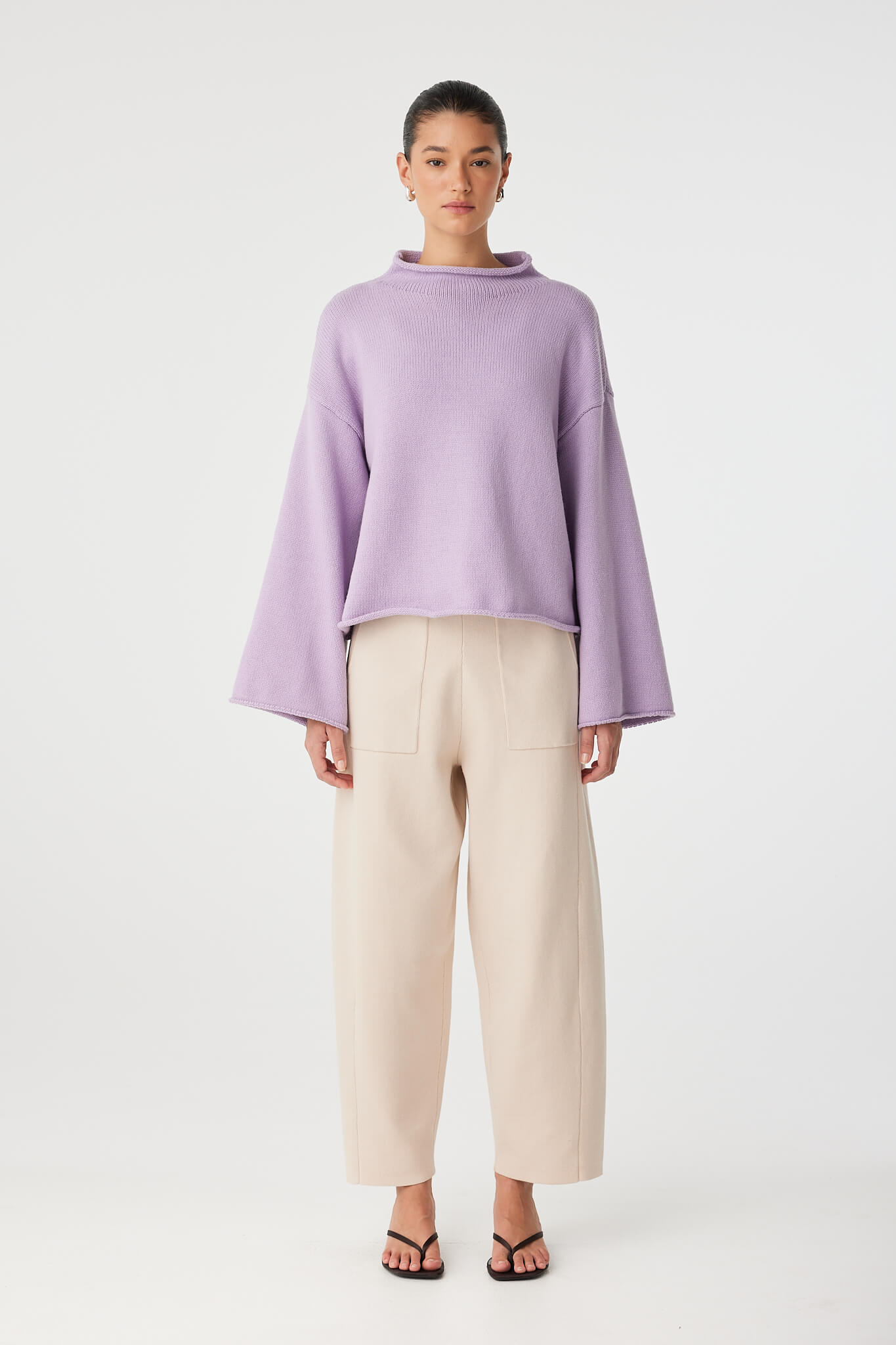 Full-body view of Maeve Sweater in lilac cotton–merino knit, paired with neutral pants.