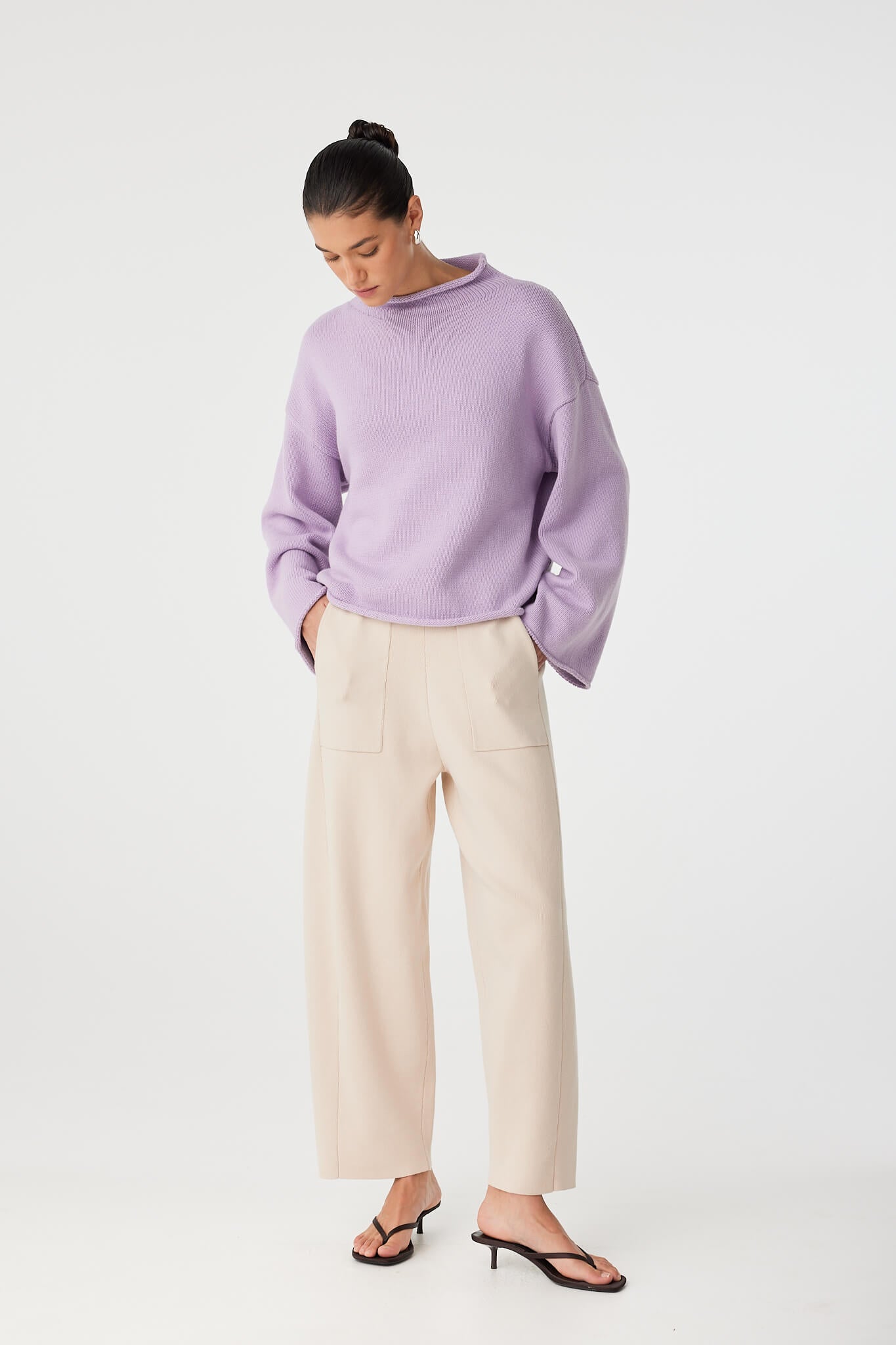 Model styles lilac sweater with slouchy ease, highlighting soft funnel neck and wide sleeves.
