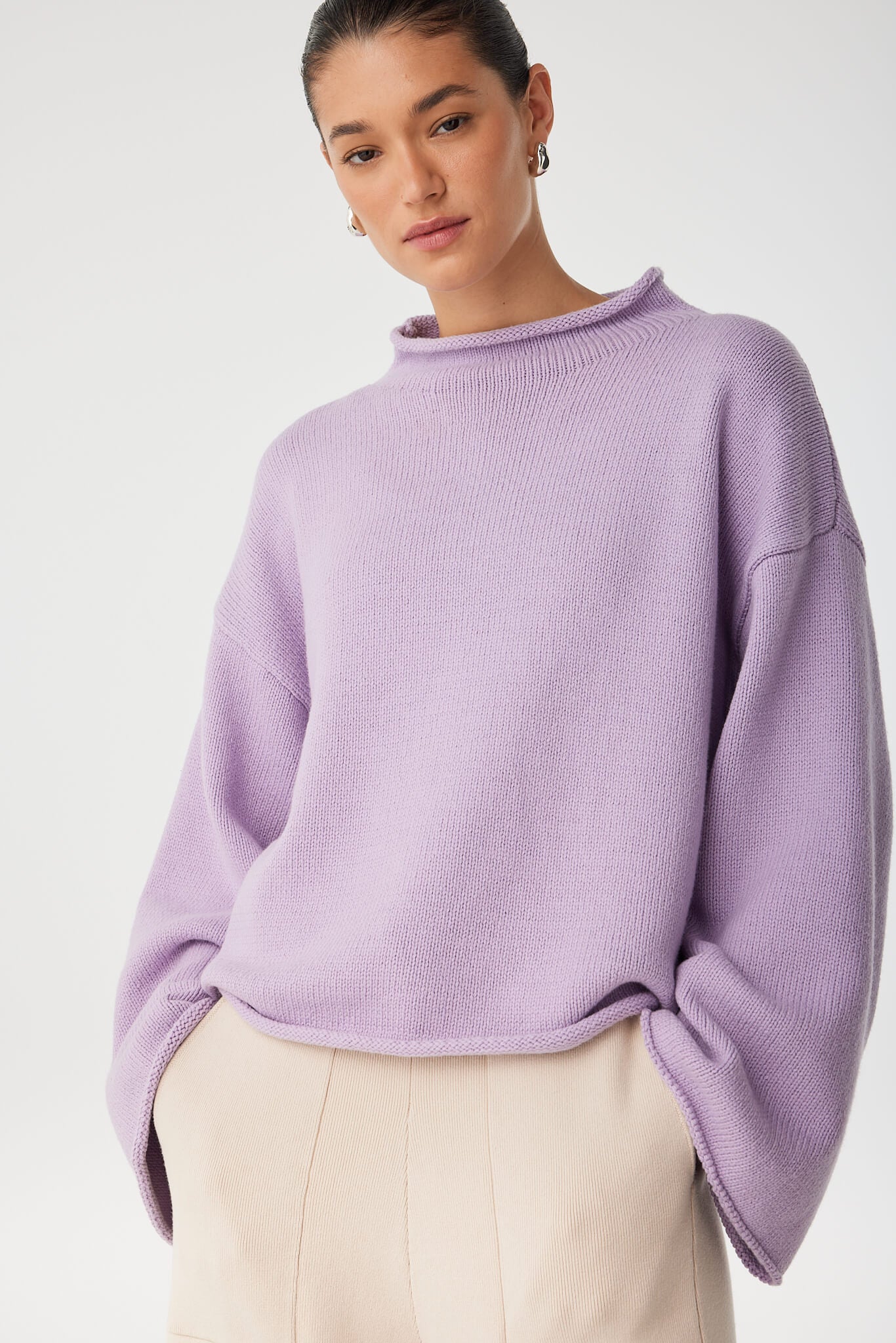 Close-up of lilac cotton–merino knit texture and funnel neckline, styled for transitional layering.