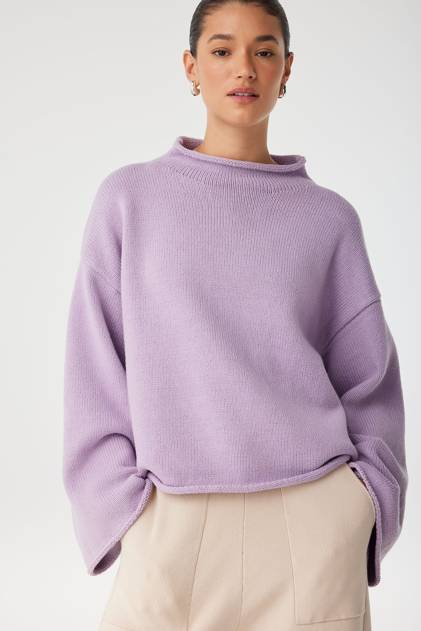 Relaxed moment in cropped lilac sweater, revealing wide sleeve line and breathable knit blend.