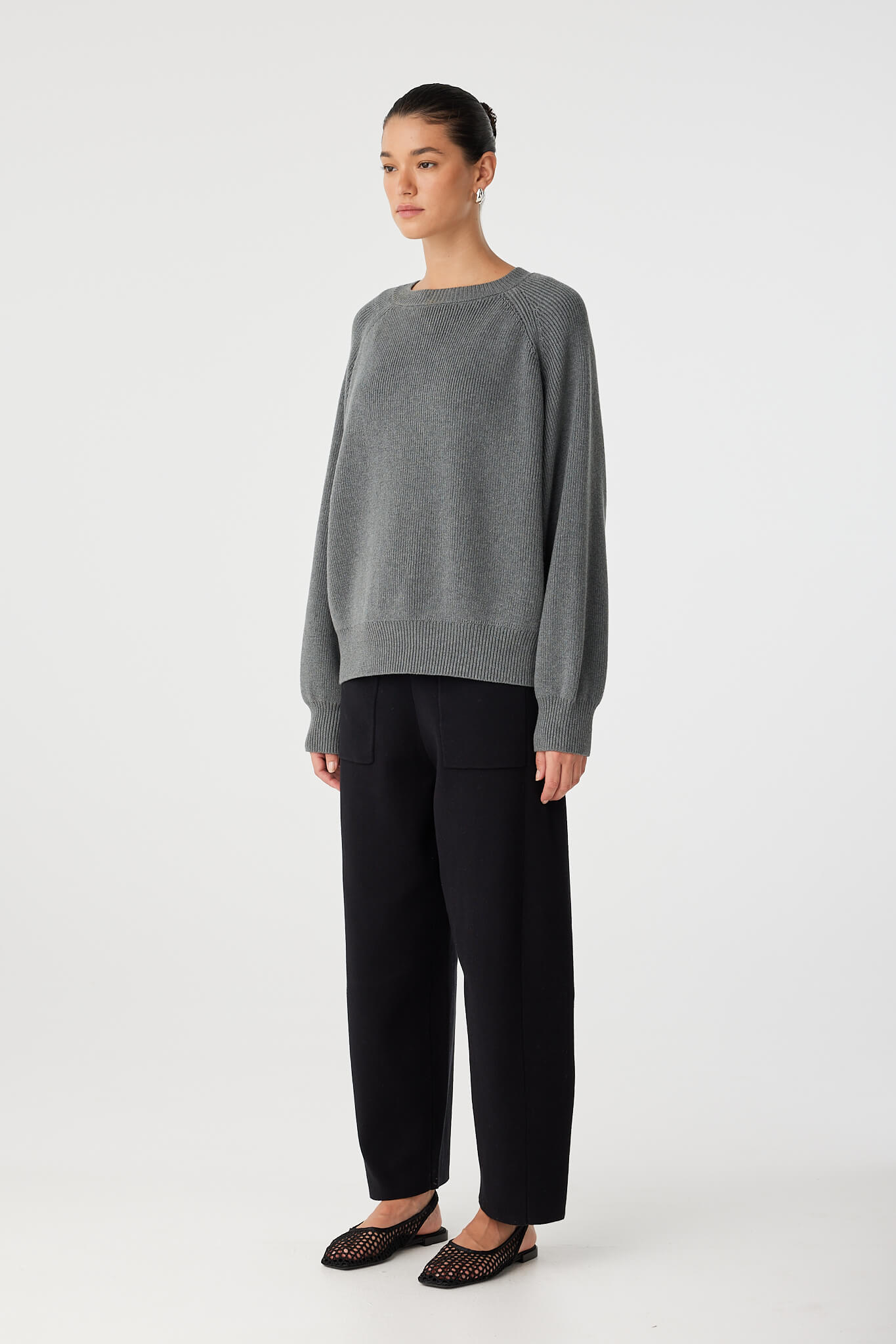 Side look of black knit pants paired with relaxed fit top, showing movement and drape.