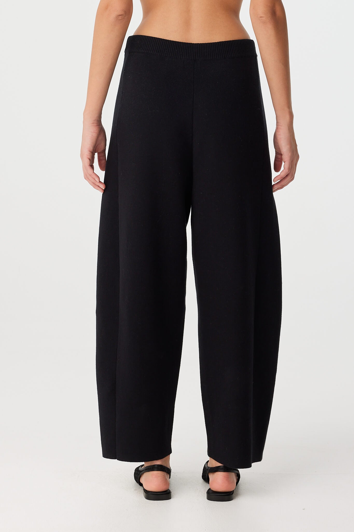 Back view of knit pant in black organic cotton with curved leg shape.