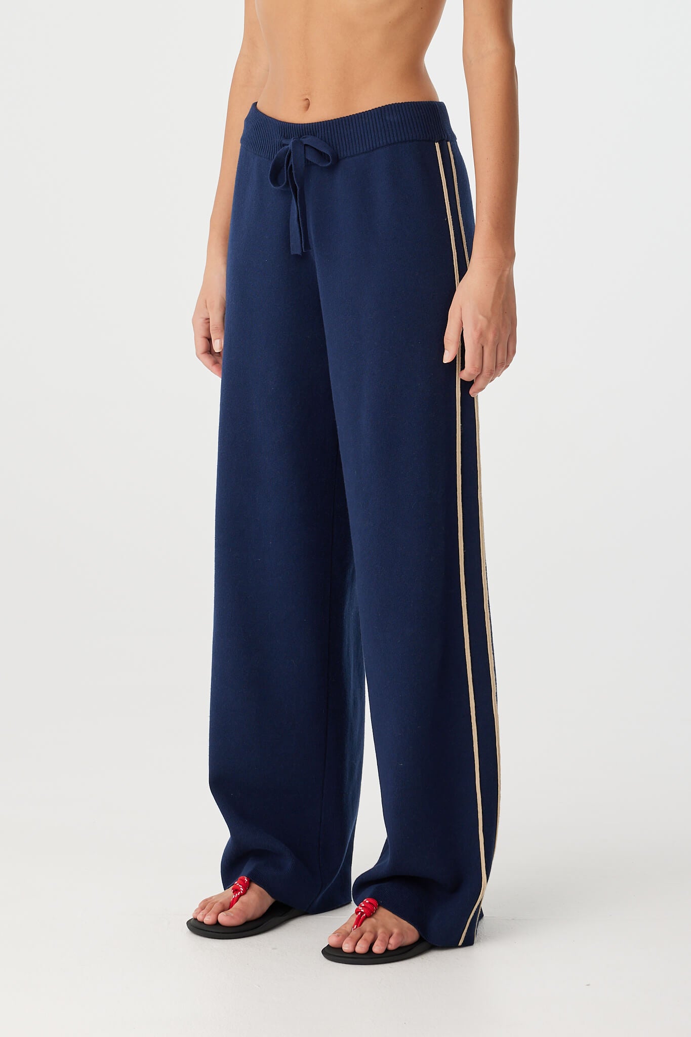 Side angle showing cream contrast stripe detailing on navy wide-leg pants.