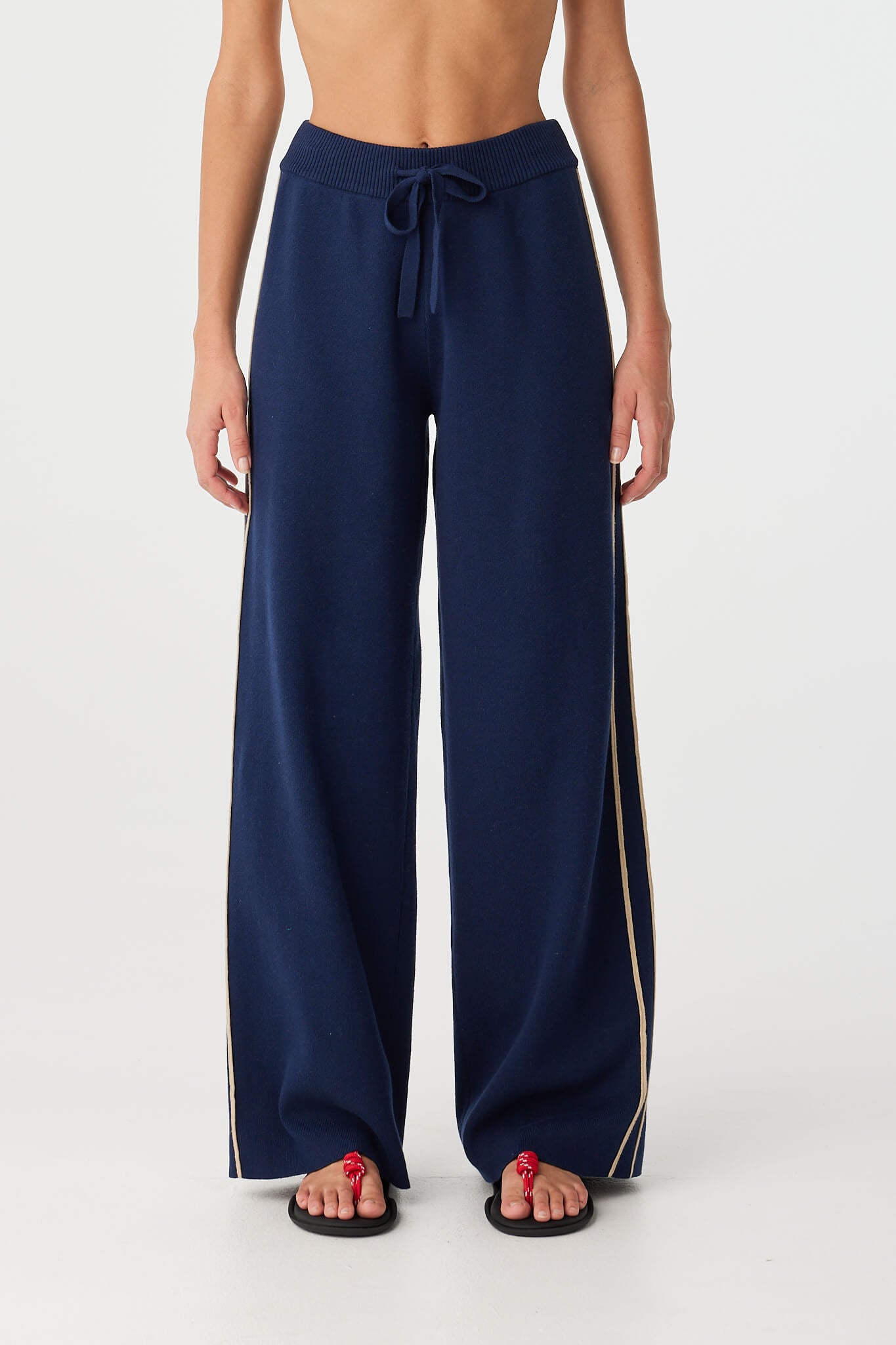 Model wears navy wide leg pant with contrast side stripes and drawcord waistband.