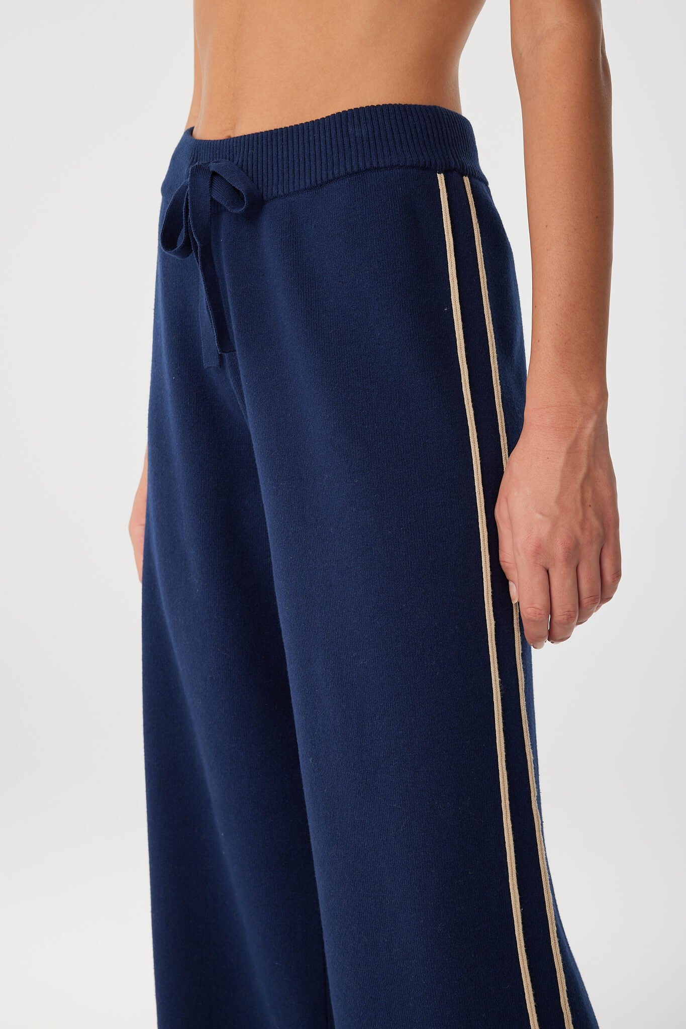 Detail of drawcord waist and side stripe in soft stretch navy knit pant.