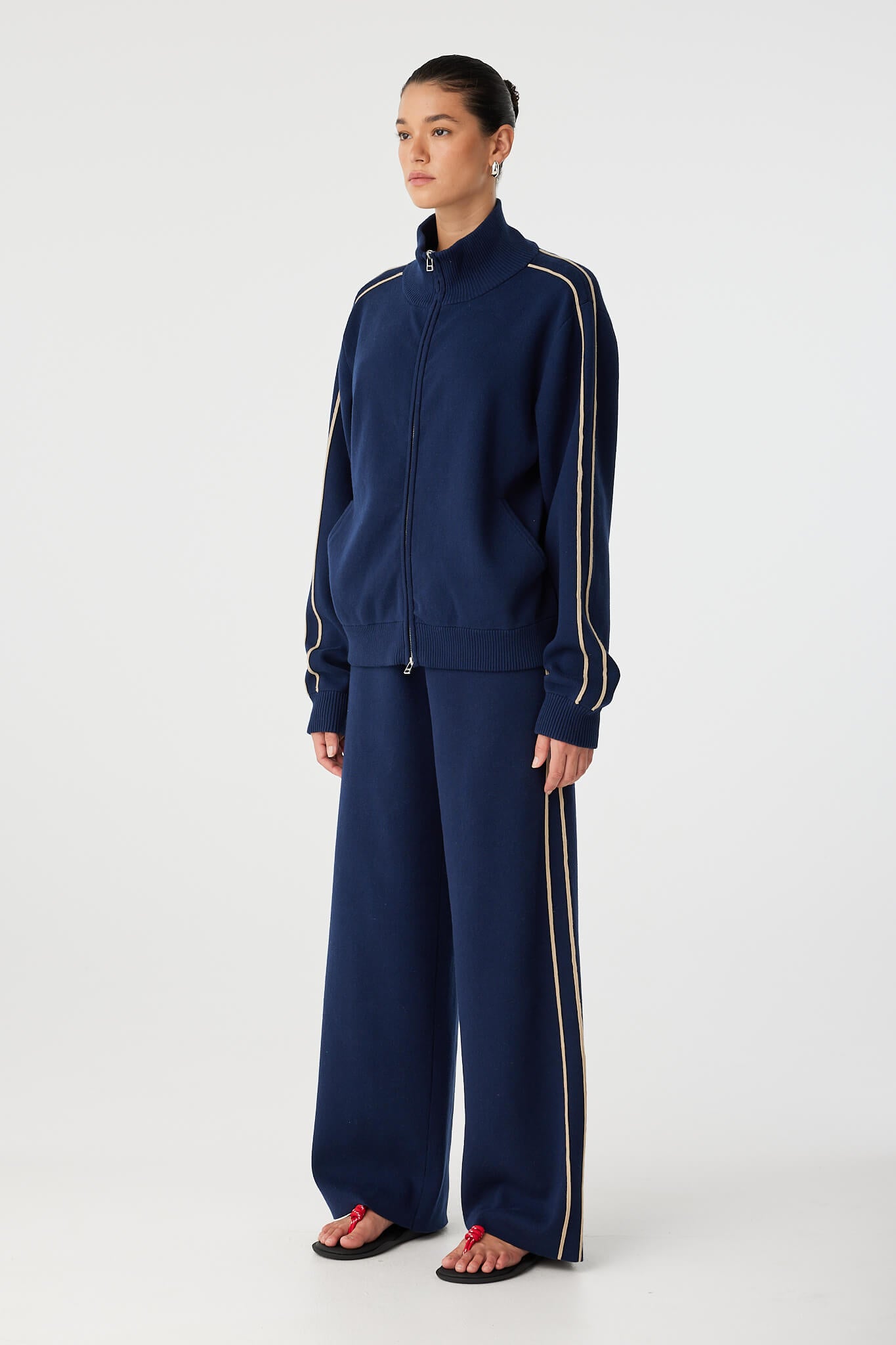Side angle of sporty zip jacket showing sleeve stripe detail and ribbed cuff.