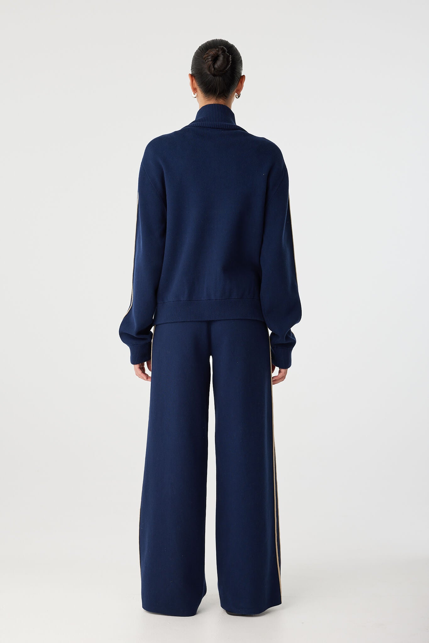 Back view of navy funnel-neck jacket with soft structure and athletic detailing.