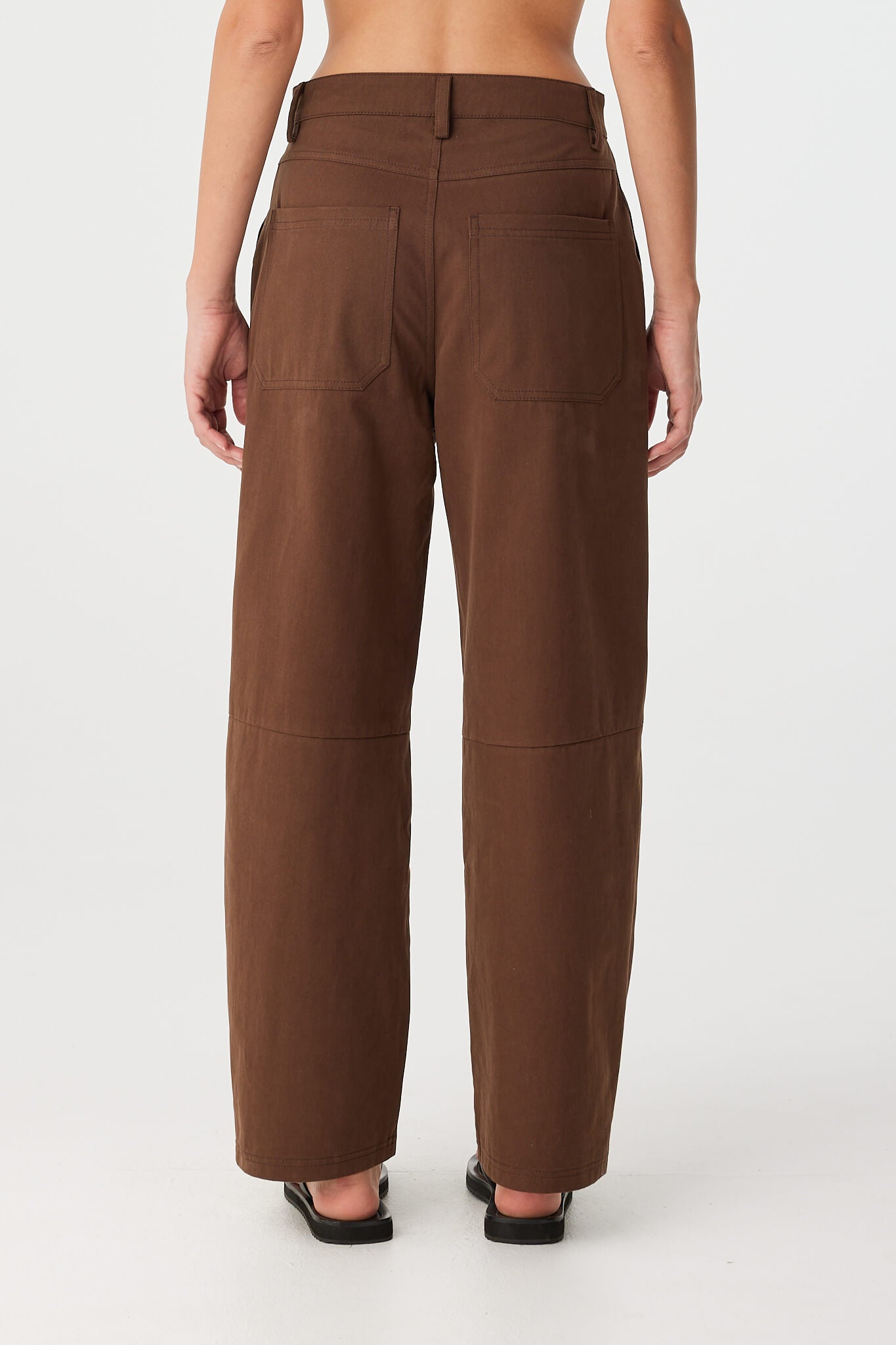 Back view of chocolate cotton pants showing patch pockets and curved leg fit.