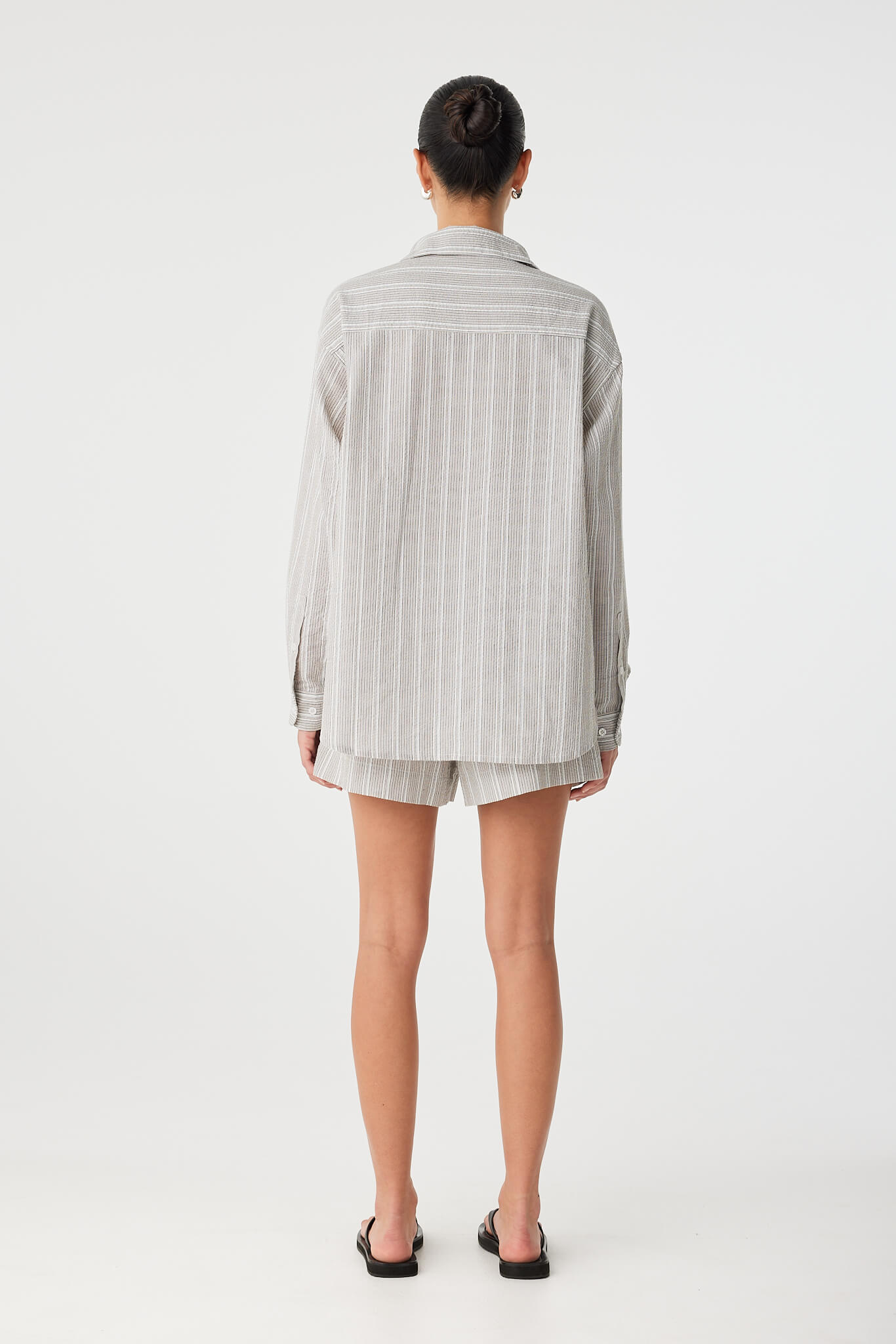 Back view of the shirt revealing deep pleats and casual length.