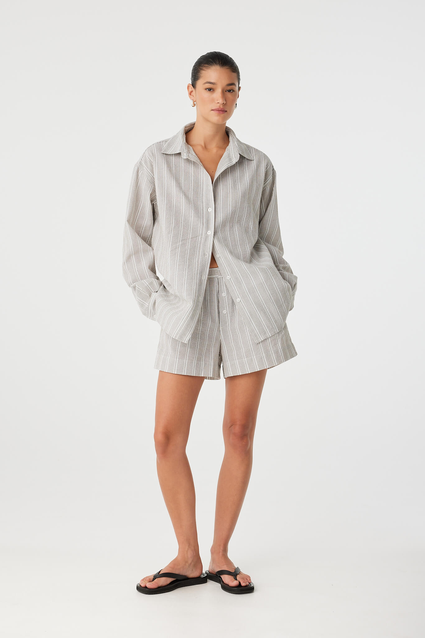 Side view of model wearing relaxed cotton stripe shirt with matching Ines Short, styled open.