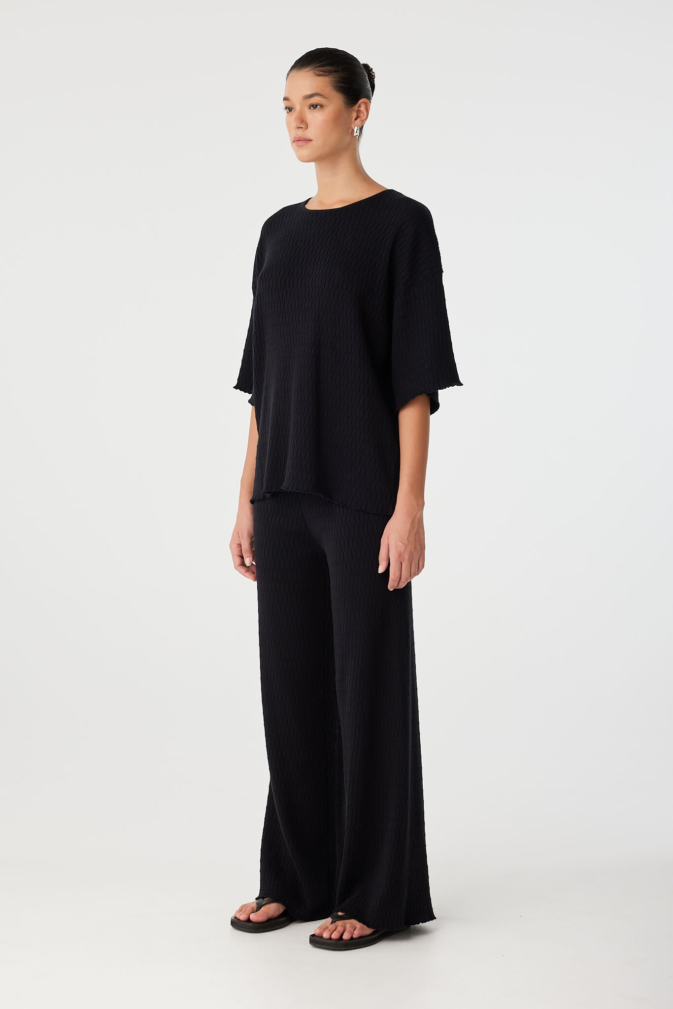 Three-quarter front angle of oversized black T-shirt with relaxed sleeves and modern fit.
