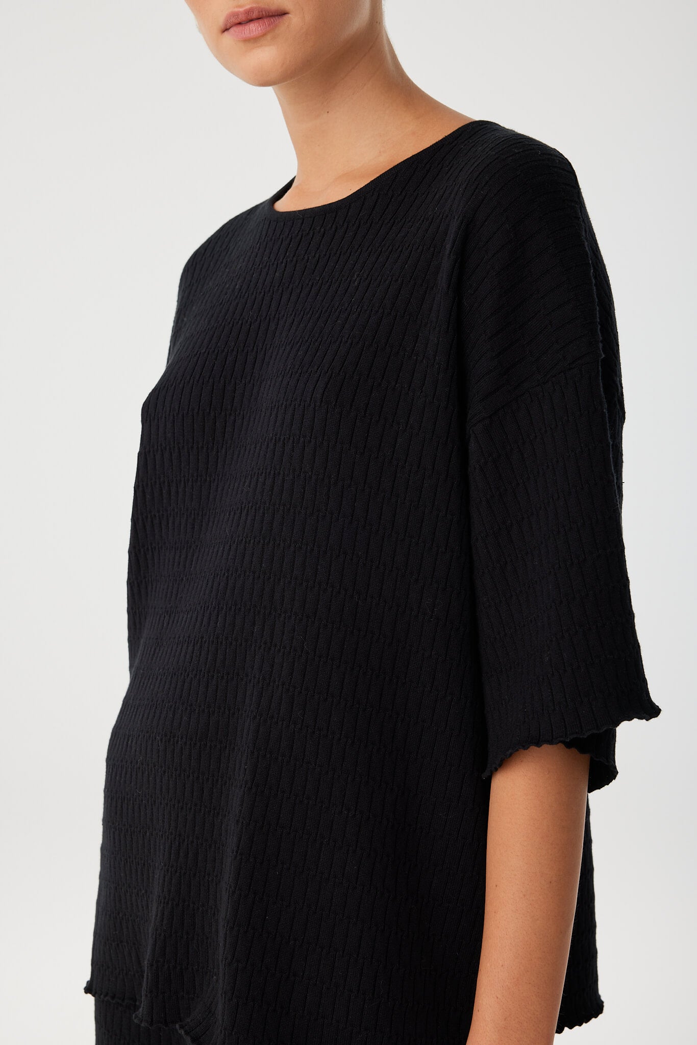 Detail shot of shoulder and sleeve highlighting the cotton knit texture and neckline finish.