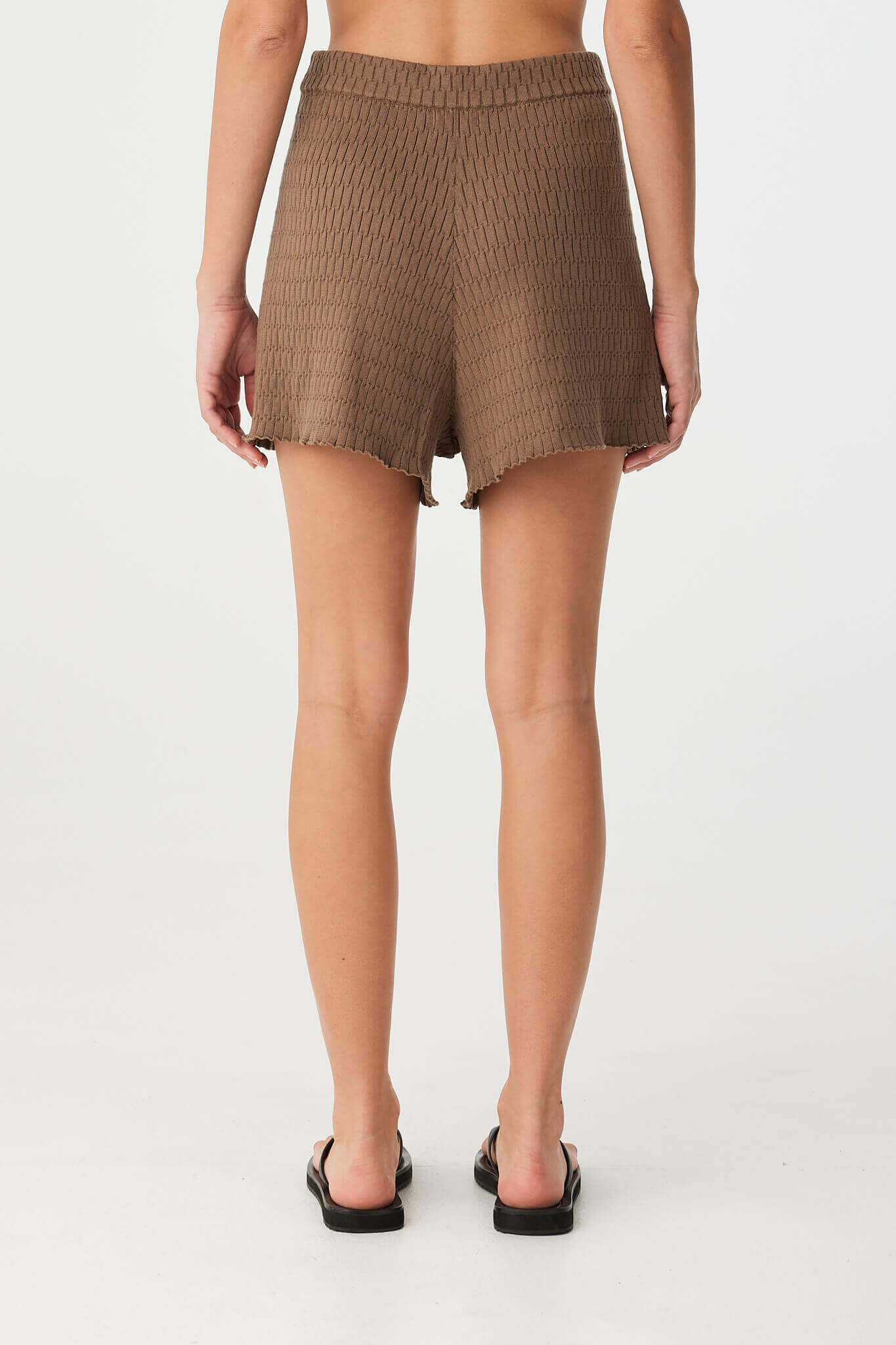 Back view of organic cotton shorts in deep cacao, with relaxed silhouette and clean knit finish at hem.