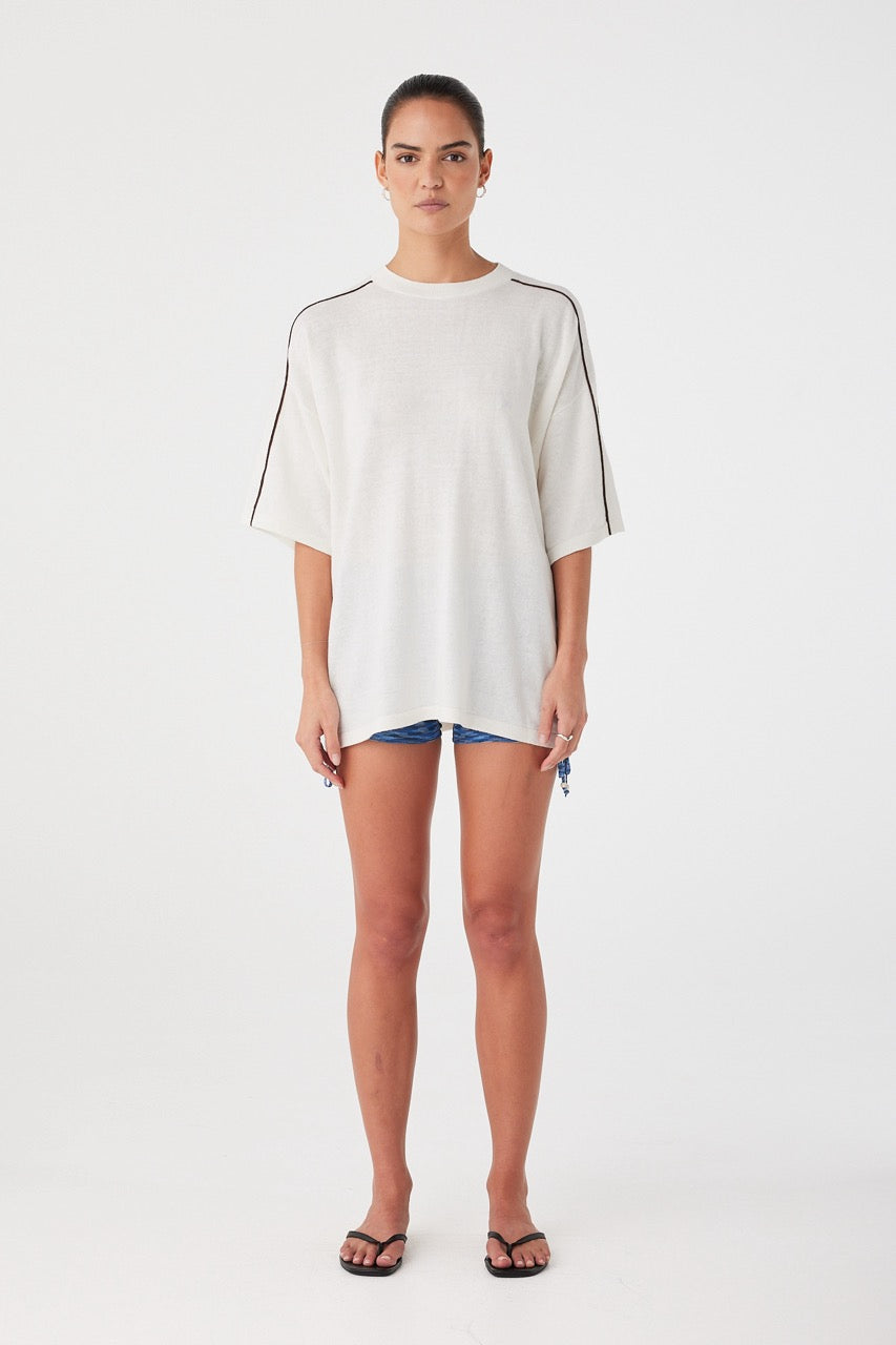 Relaxed oversized tee in cream with contrast stripe detail. Styled casually over shorts for lightweight summer layering.