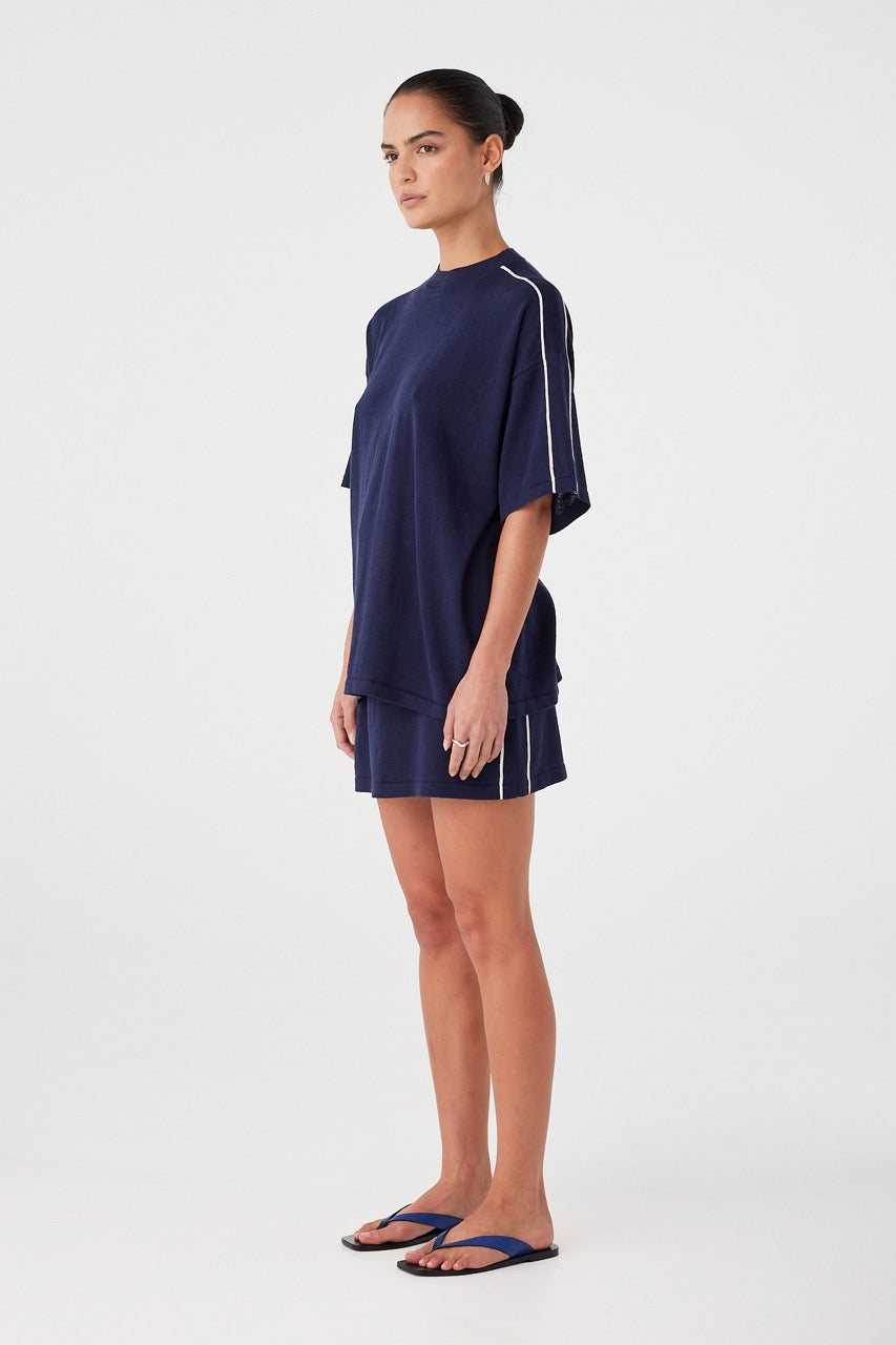 Side angle showing relaxed drape and sleeve detail of navy oversized tee. Lightweight and designed for warm-weather comfort.