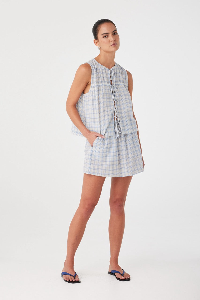 Model styled in powder blue check mini skirt with relaxed drape and high-rise fit. Lightweight texture ideal for layering.