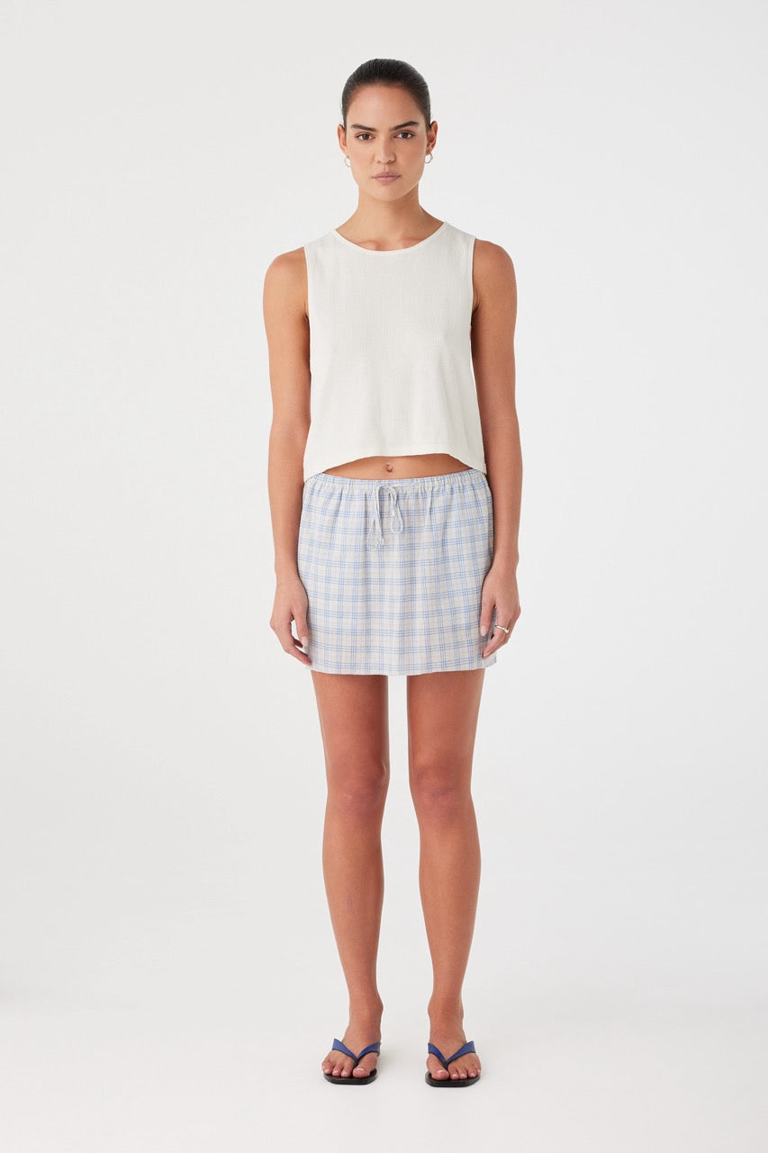 Model wears powder blue check mini skirt in lightweight cotton. Features gathered waistband with drawcord and relaxed fit.
