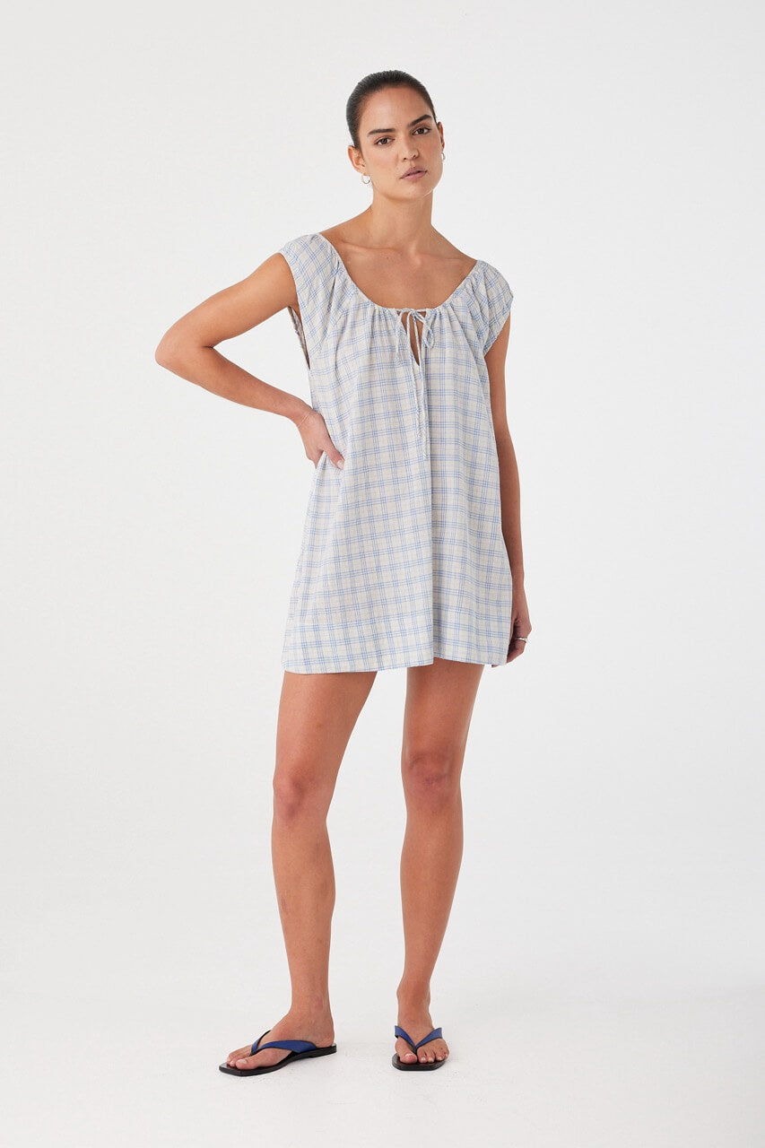 Model in flared mini dress with tie neckline and keyhole front. Powder blue check pattern in soft, airy cotton.
