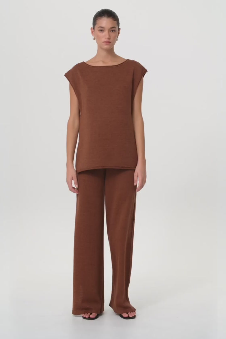 Model moves in clay wide-leg knit pant and matching top, showing natural drape, side pleats, and relaxed fit in motion.