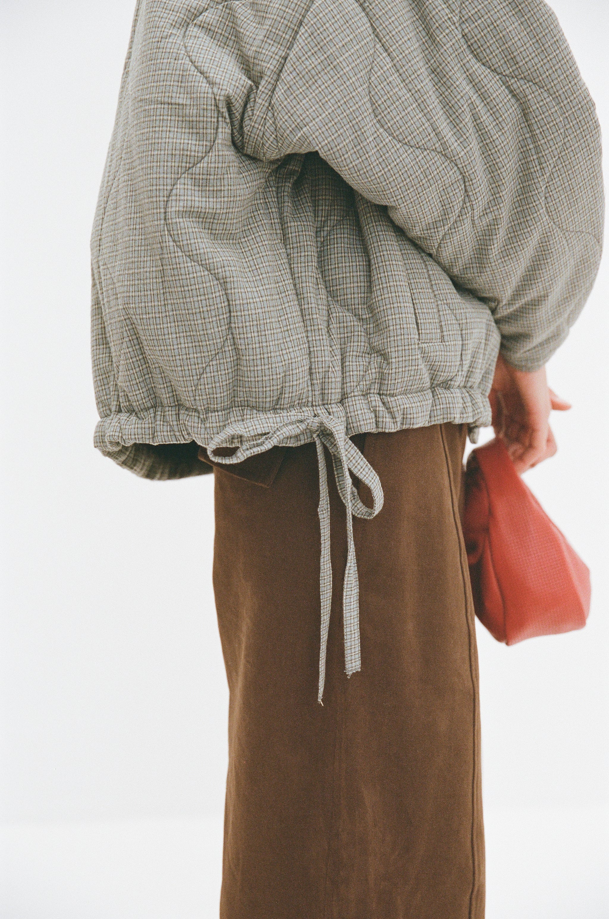 Close detail of Matteo Jacket blue check, quilted cotton texture with drawstring hem tie.