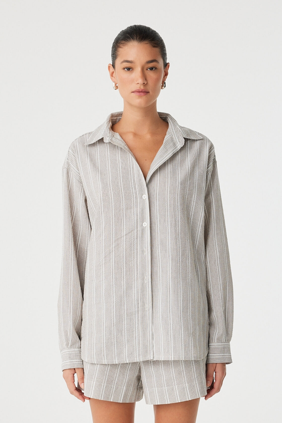 Front view of oversized striped cotton shirt with soft drape and open neckline.