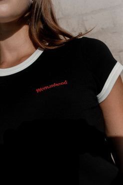Womanhood embroidery detail on black baby tee