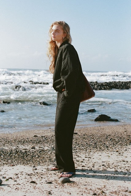 Black Akira Pant and black wren bomber jacket worn outdoors by the beach