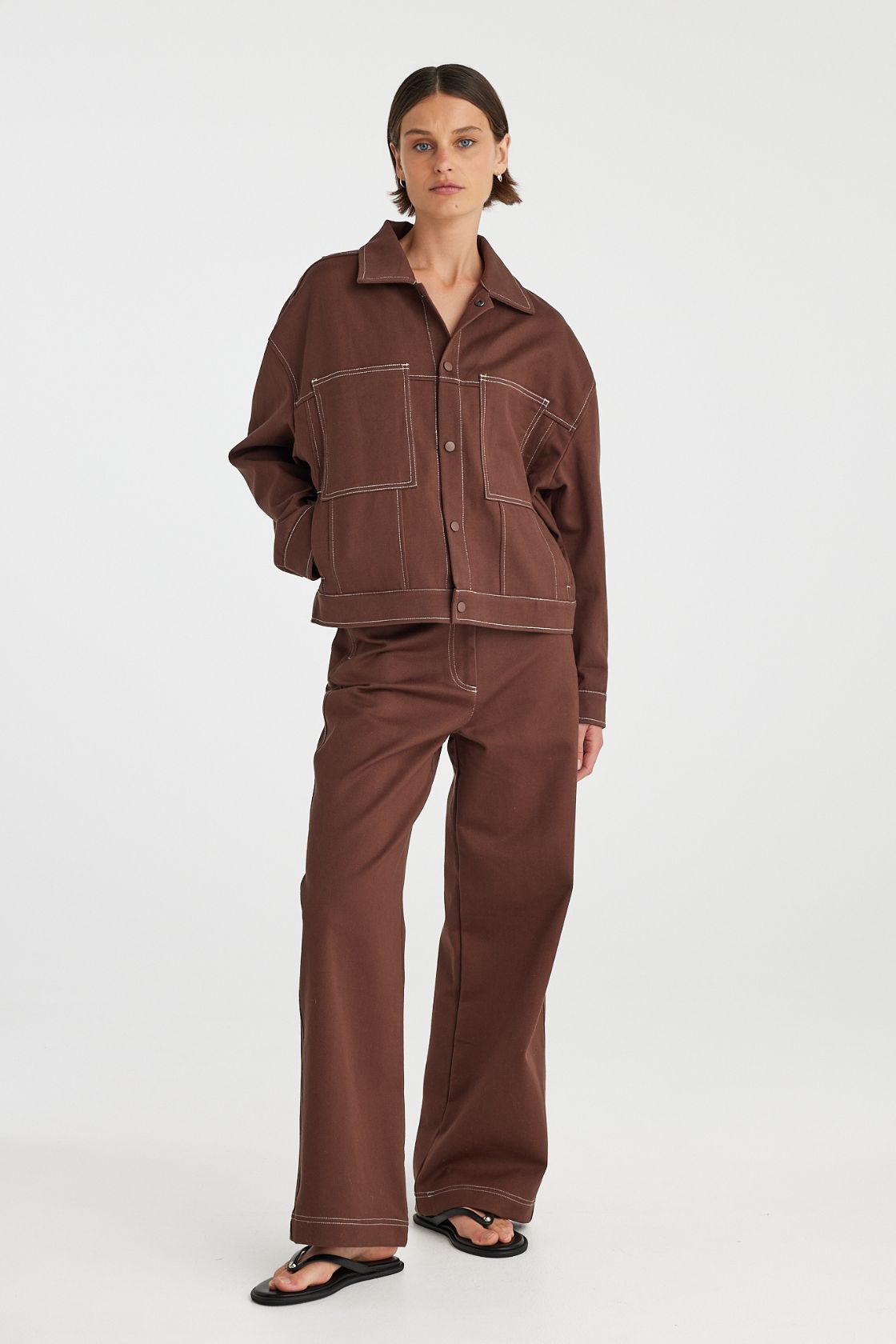 Angled front view of brown jacket showing snap button closure