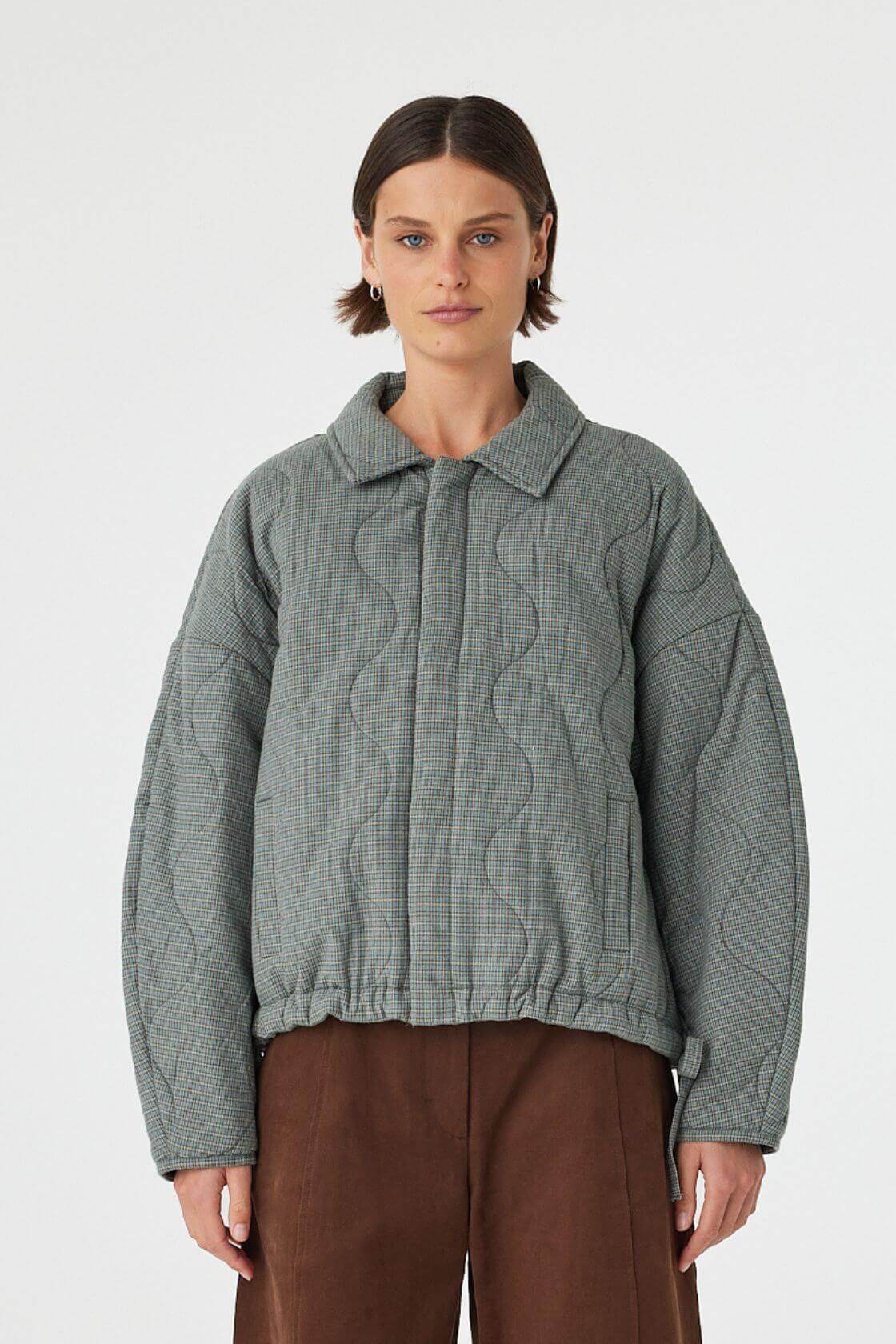 Model wearing Matteo Jacket in blue check, quilted cotton jacket with slouchy fit and drawstring hem, front view.