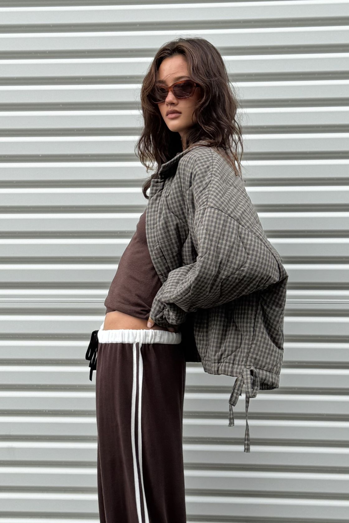 Side profile of the Matteo Jacket in Olive & Teal Check, showing the oversized quilted shape, dropped shoulder, rounded sleeve and adjustable side tie detail.