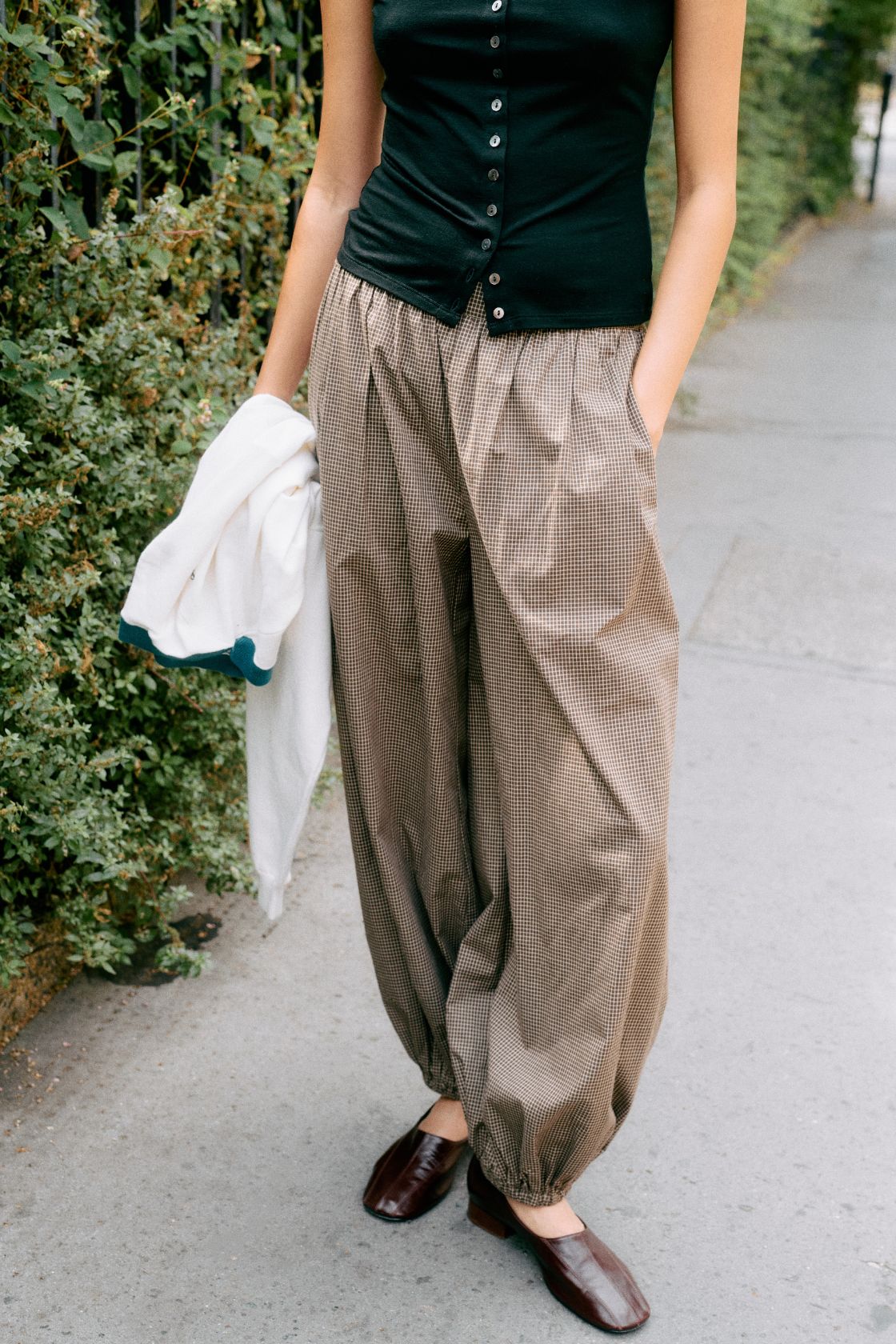 Model wearing the elina balloon pants in chocolate check with black button up top and brown loafers
