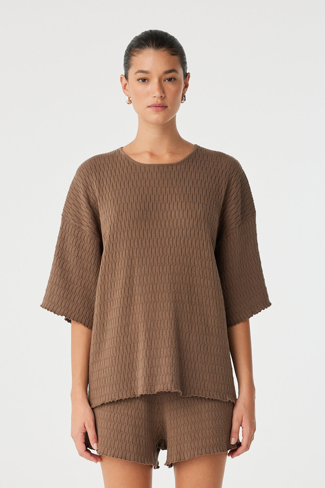 Model wears oversized textured cotton tee in cacao, styled with matching knit shorts, soft structure for elevated lounge or casual layering.