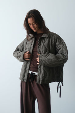 Studio image of the Matteo Jacket in Olive & Teal Check, styled open with a chocolate brown top and matching lounge pants, showing the slouchy fit, padded sleeves and adjustable hem ties.