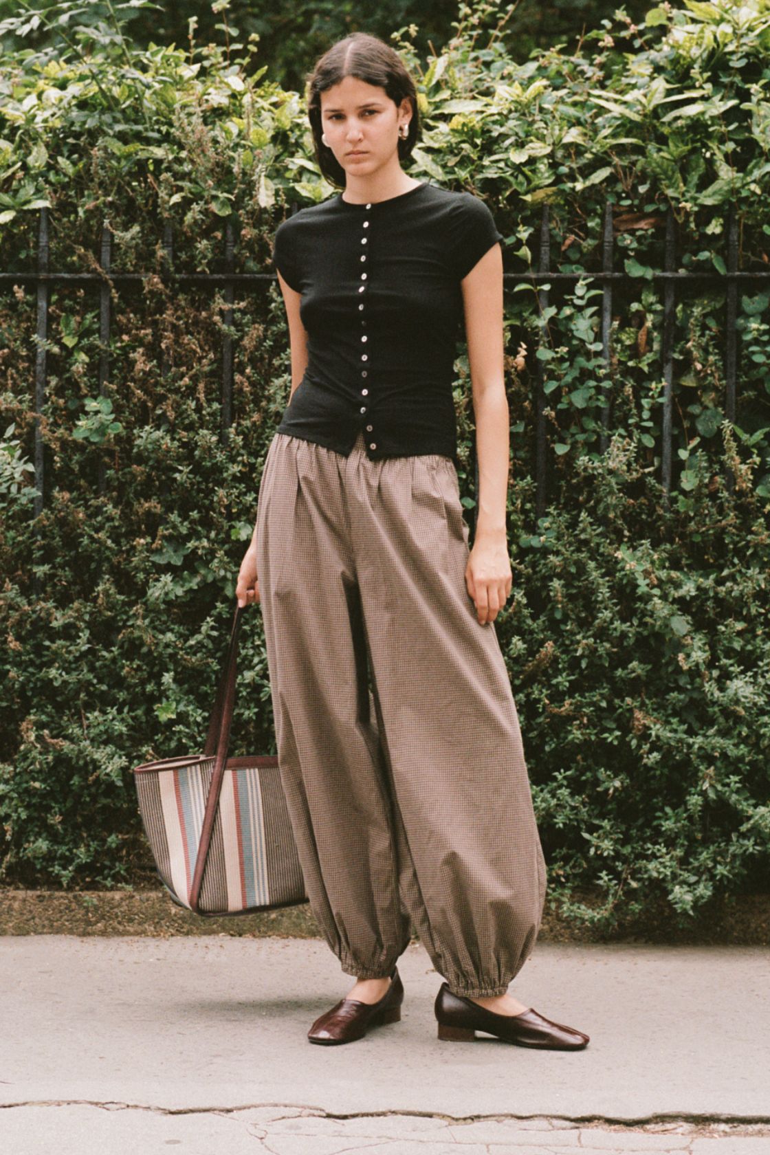 Model wearing the elina balloon pants in chocolate check with black button up top and brown loafers