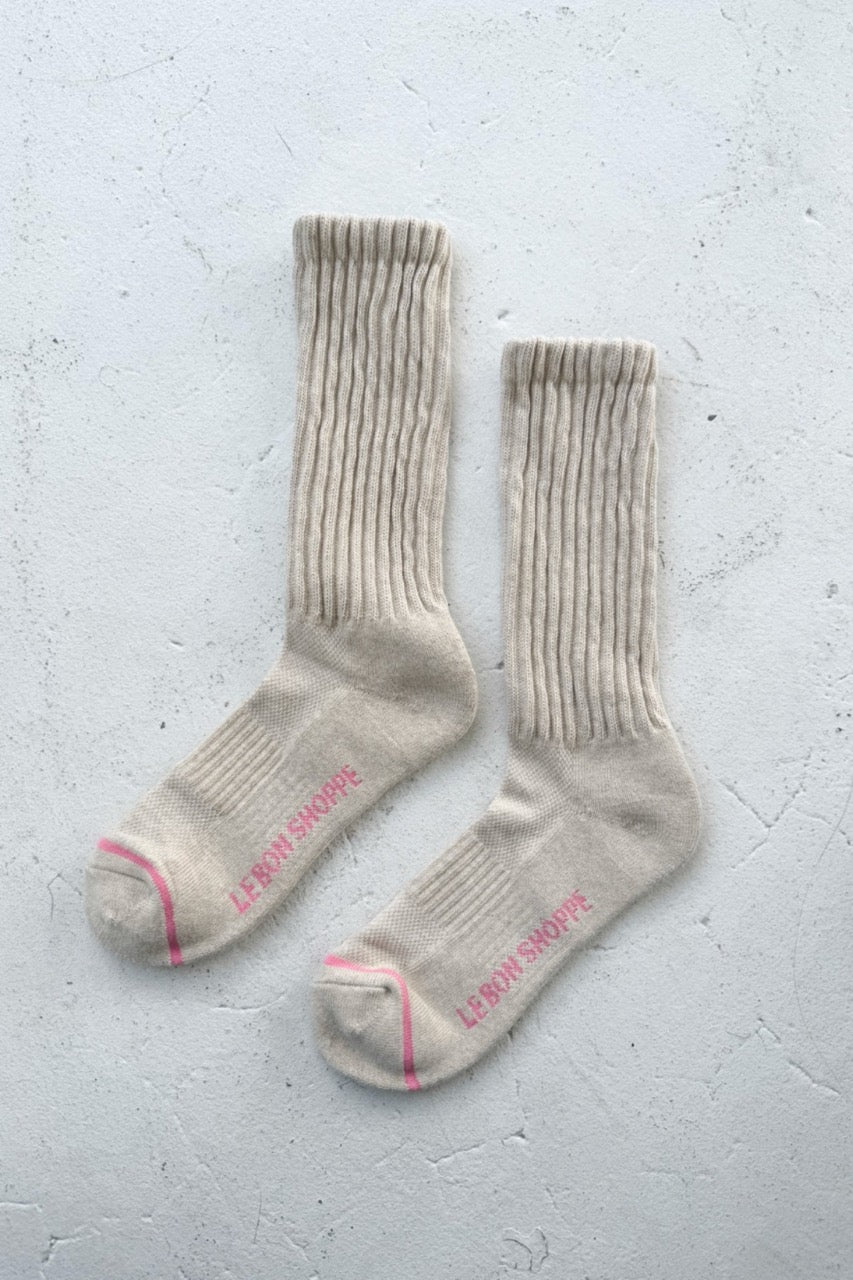 Pair of oatmeal socks with pink accents on a light gray background