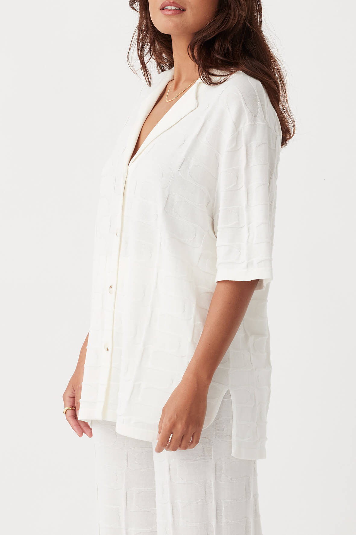 Side view of Lara Shirt in cream, showcasing oversized fit, side splits, and lightweight organic cotton knit.