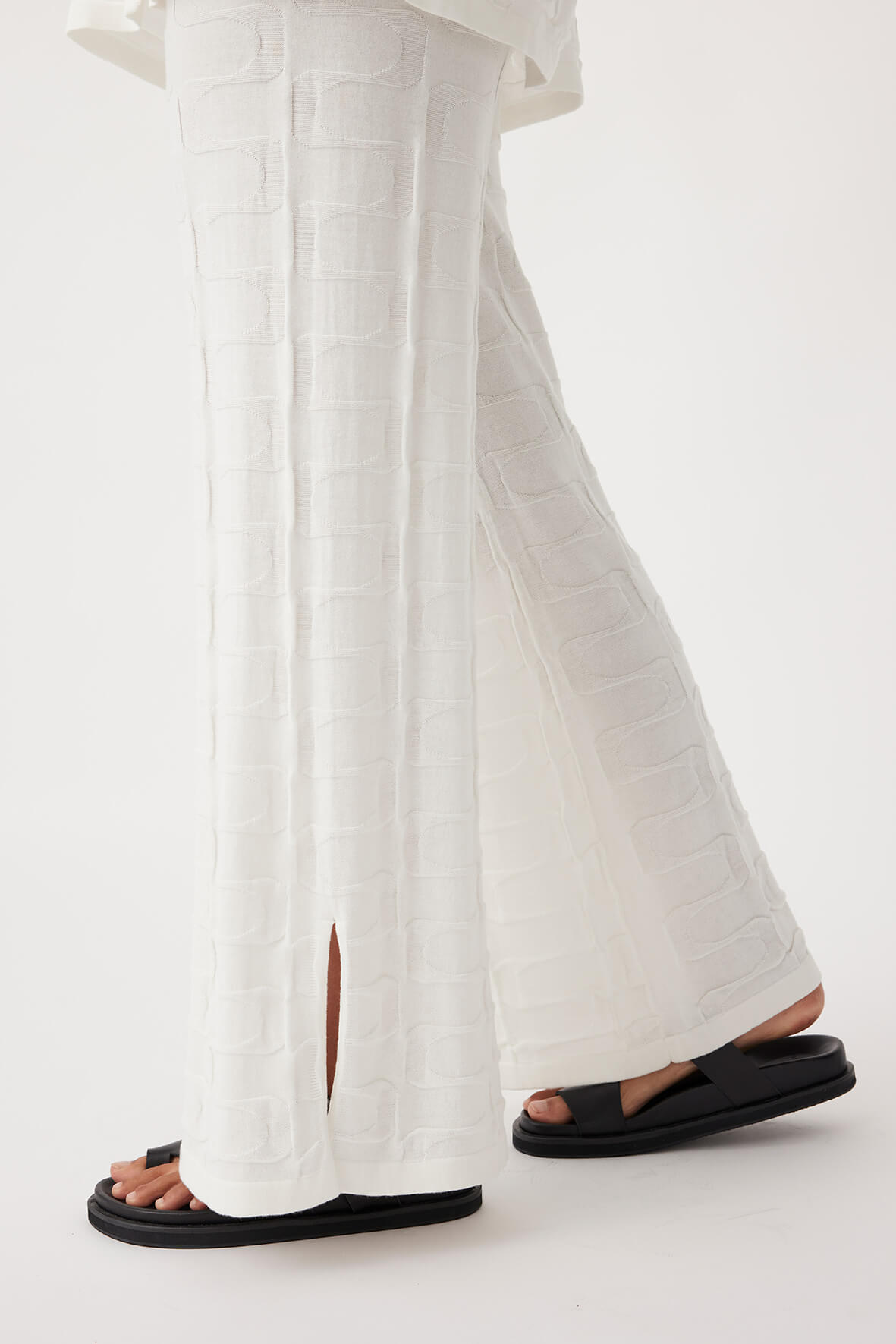 Close-up side view of Lara Pant in cream, featuring ribbed elastic waistband and side splits in lightweight organic cotton knit.