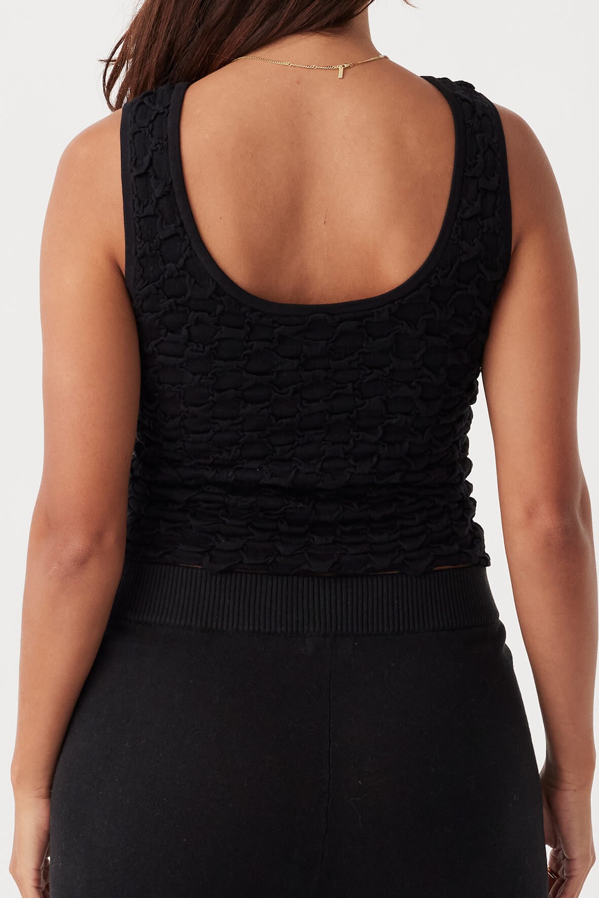 Back view of the Mila Tank in Black, showcasing its reversible scoop neck option and snug fit.