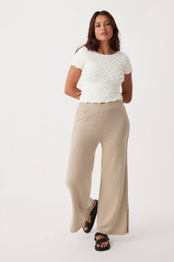 Full-body shot of Poppy Pant, relaxed fit with ribbed elastic waist, pleats, and ties, made from eco-friendly organic cotton-linen blend.