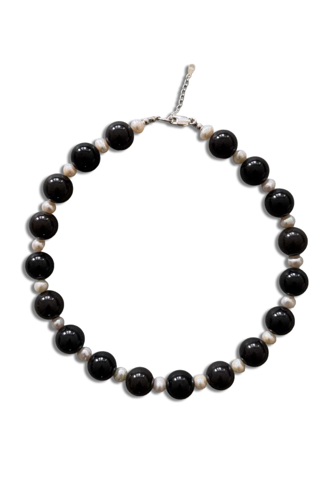 A beaded necklace featuring alternating large glossy black beads and smaller matte off-white beads, completed with a silver-tone lobster clasp, shown on a plain white background.