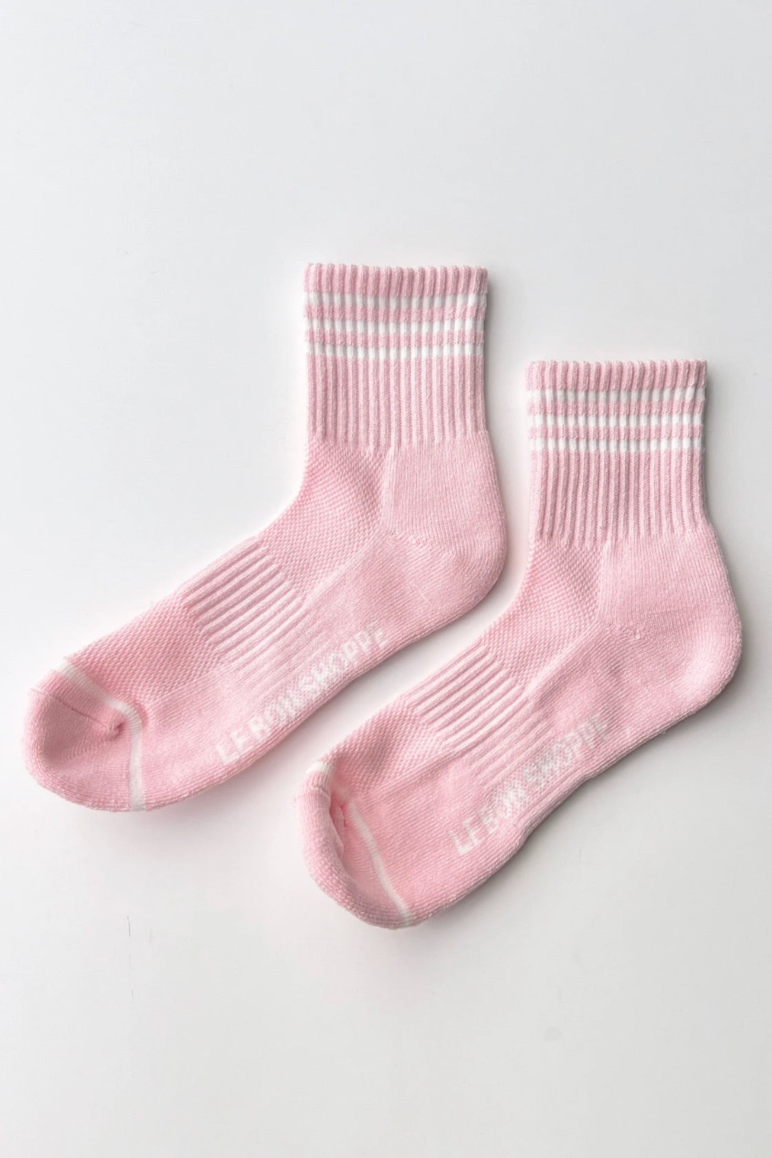Pair of pink socks with white stripes on a light gray background