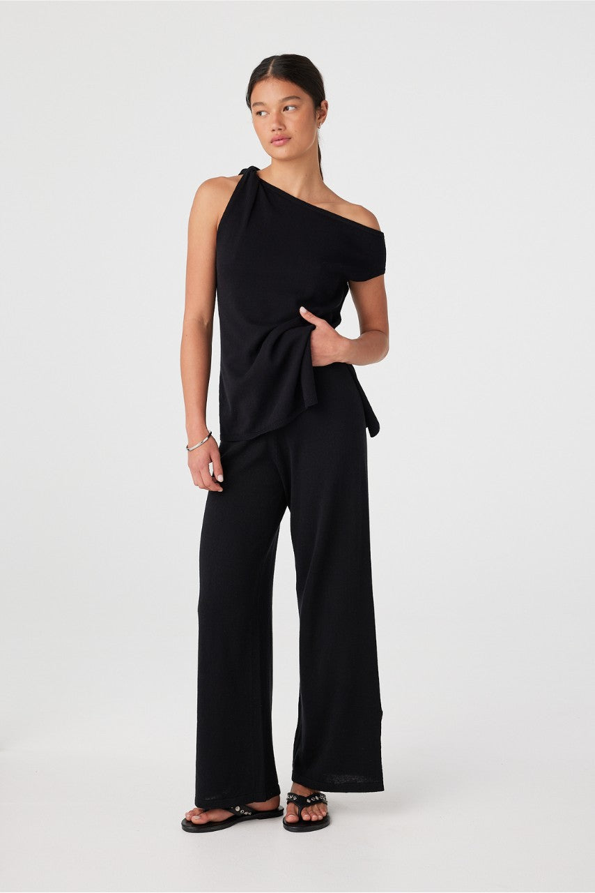 Side view close to hem showing movement of black wide-leg pants