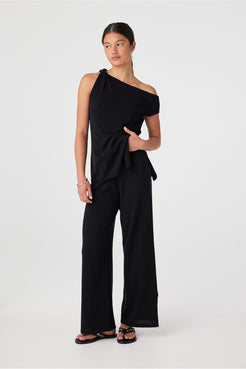 Side view close to hem showing movement of black wide-leg pants