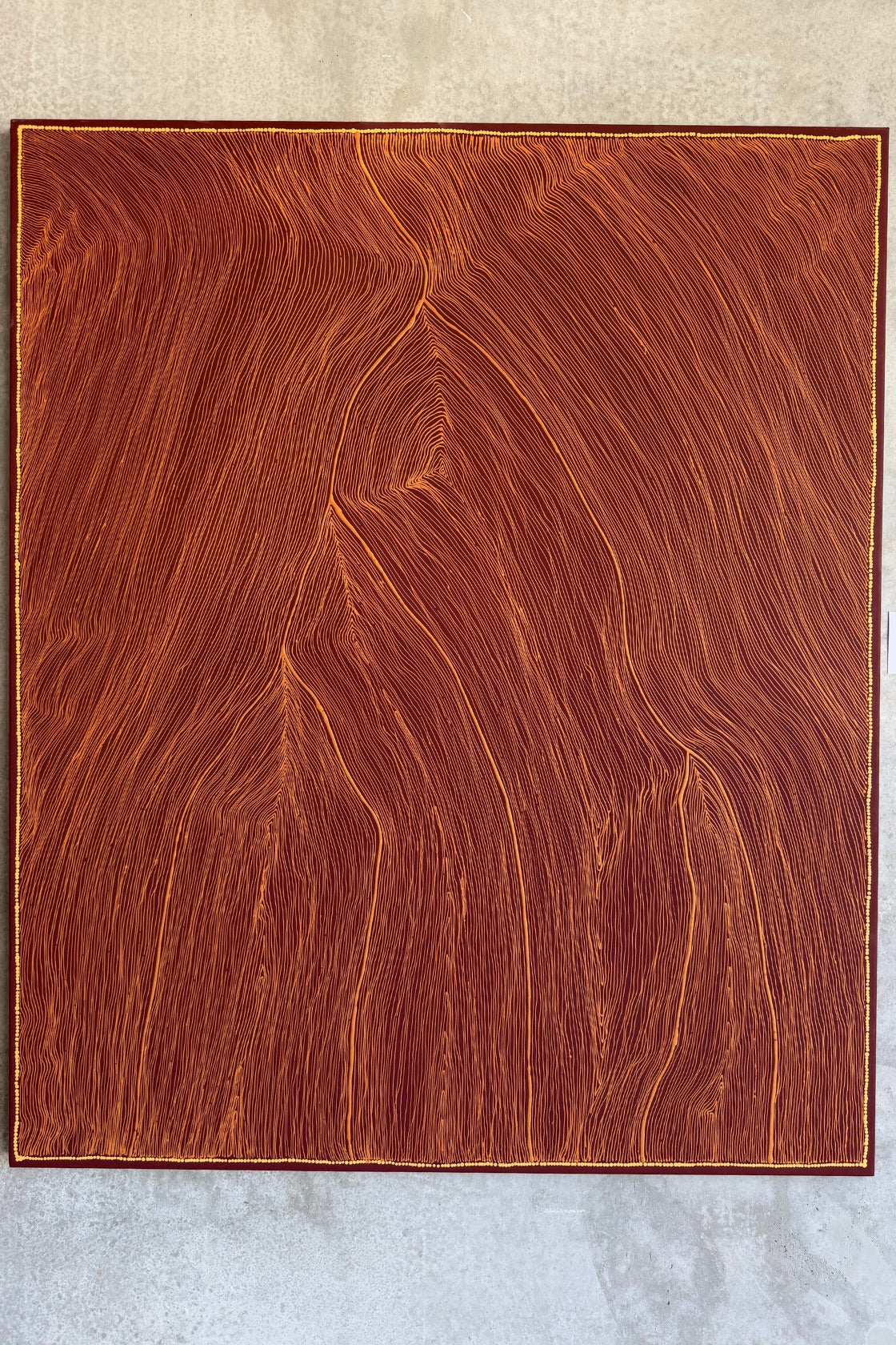 A square wooden board or panel with a rich reddish-brown wood grain pattern, photographed flat against a light gray textured background.