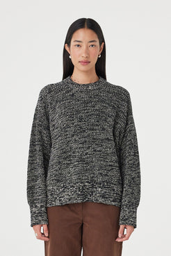 Full-length front view of the Solene Sweater in black and taupe featuring a chunky marled knit texture, oversized silhouette and ribbed hem styled with espresso pants