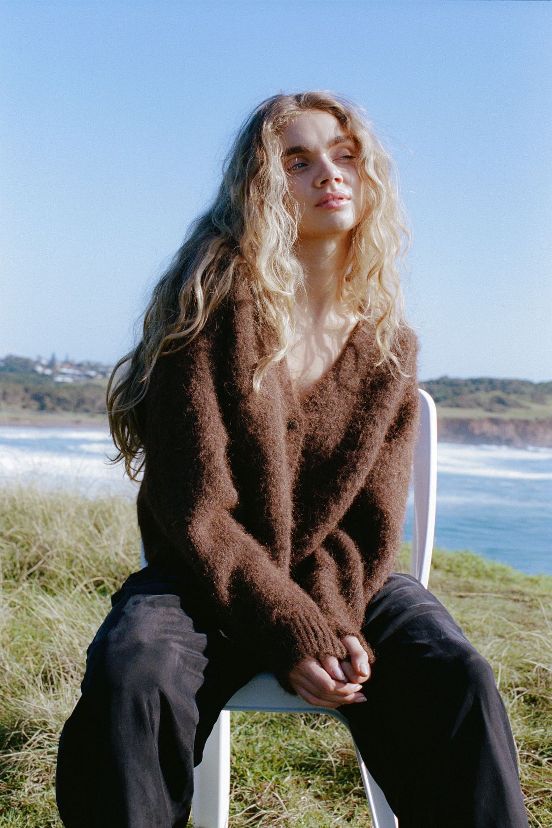 Lifestyle image of espresso fluffy cardigan worn outdoors by the ocean