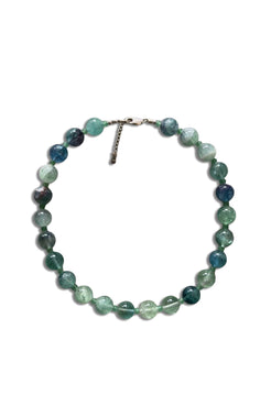 A beaded necklace made of round, polished gemstone beads in shades of green, blue, and teal, with a small silver clasp, shown on a plain white background.