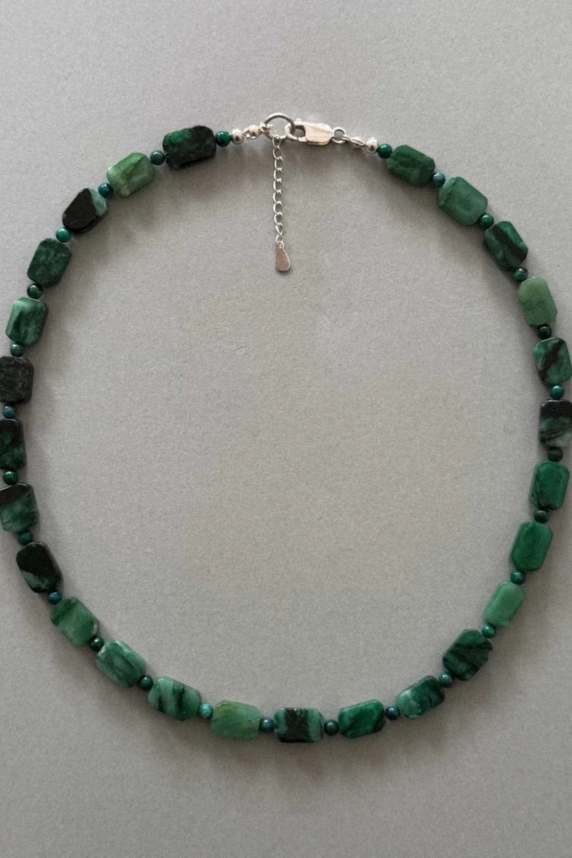 This item is one-of-one and truly unique. Handcrafted using natural green muscovite beads, strung against lapis stones and layered together in deep green tones.